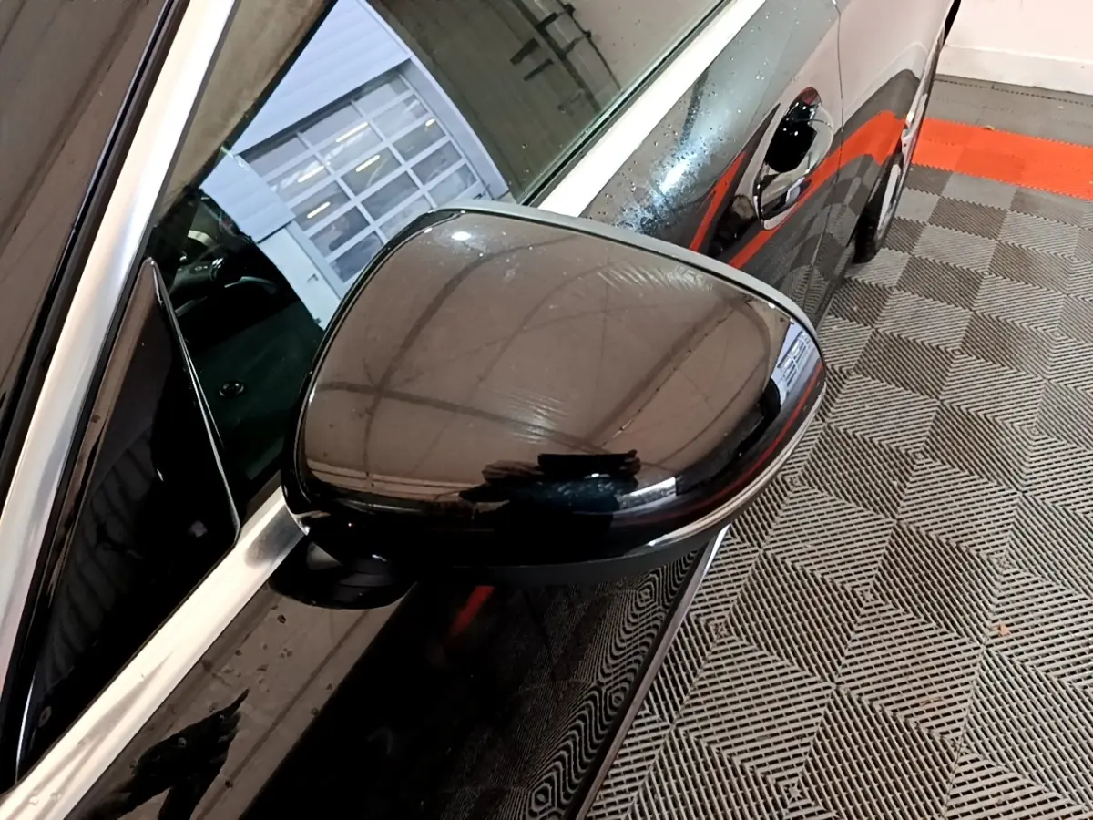 Rétroviseur côté gauche noir brillant de la Mercedes Classe A 180 AMG Line 2019 vue en gros plan sur fond de sol carrelé.