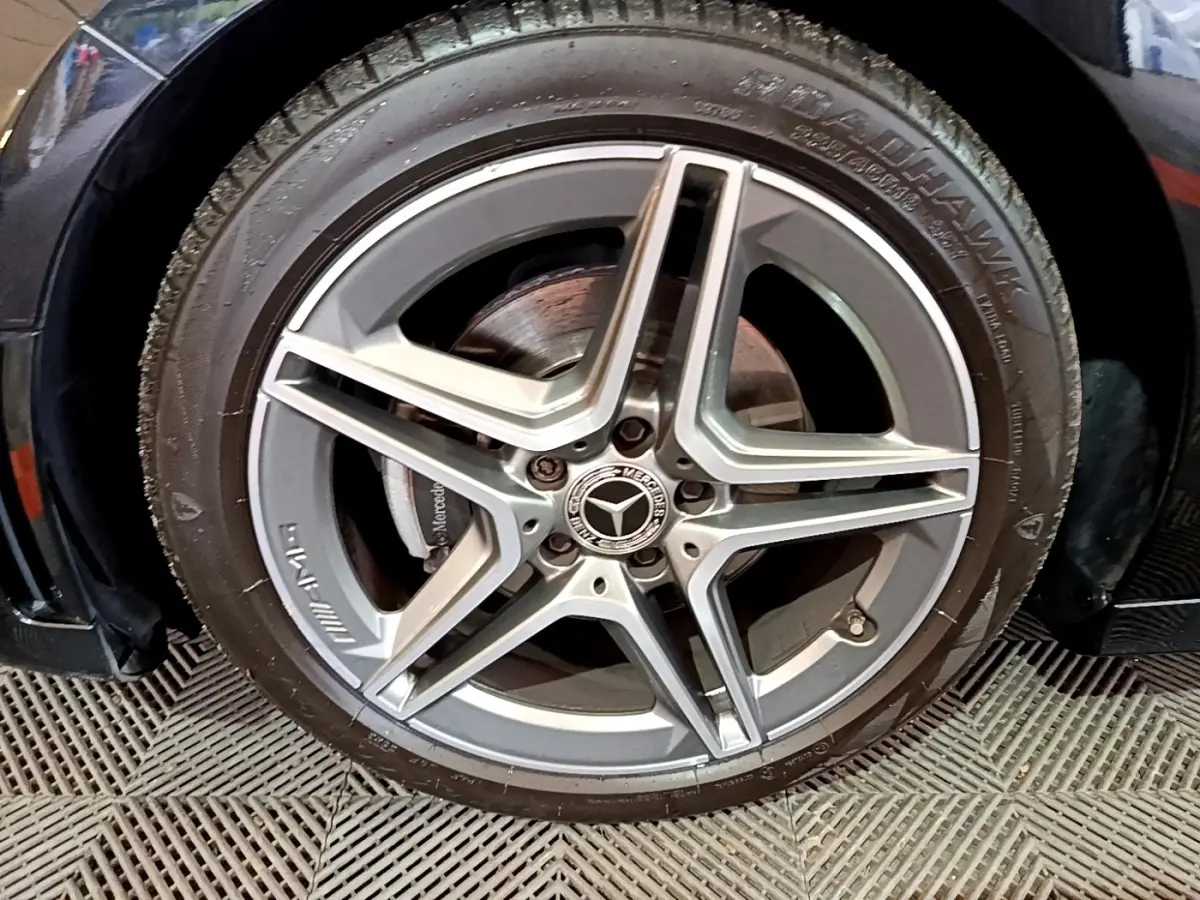 Gros plan sur la jante AMG en alliage argentée d'une Mercedes Classe A 180 AMG Line noire, côté gauche.