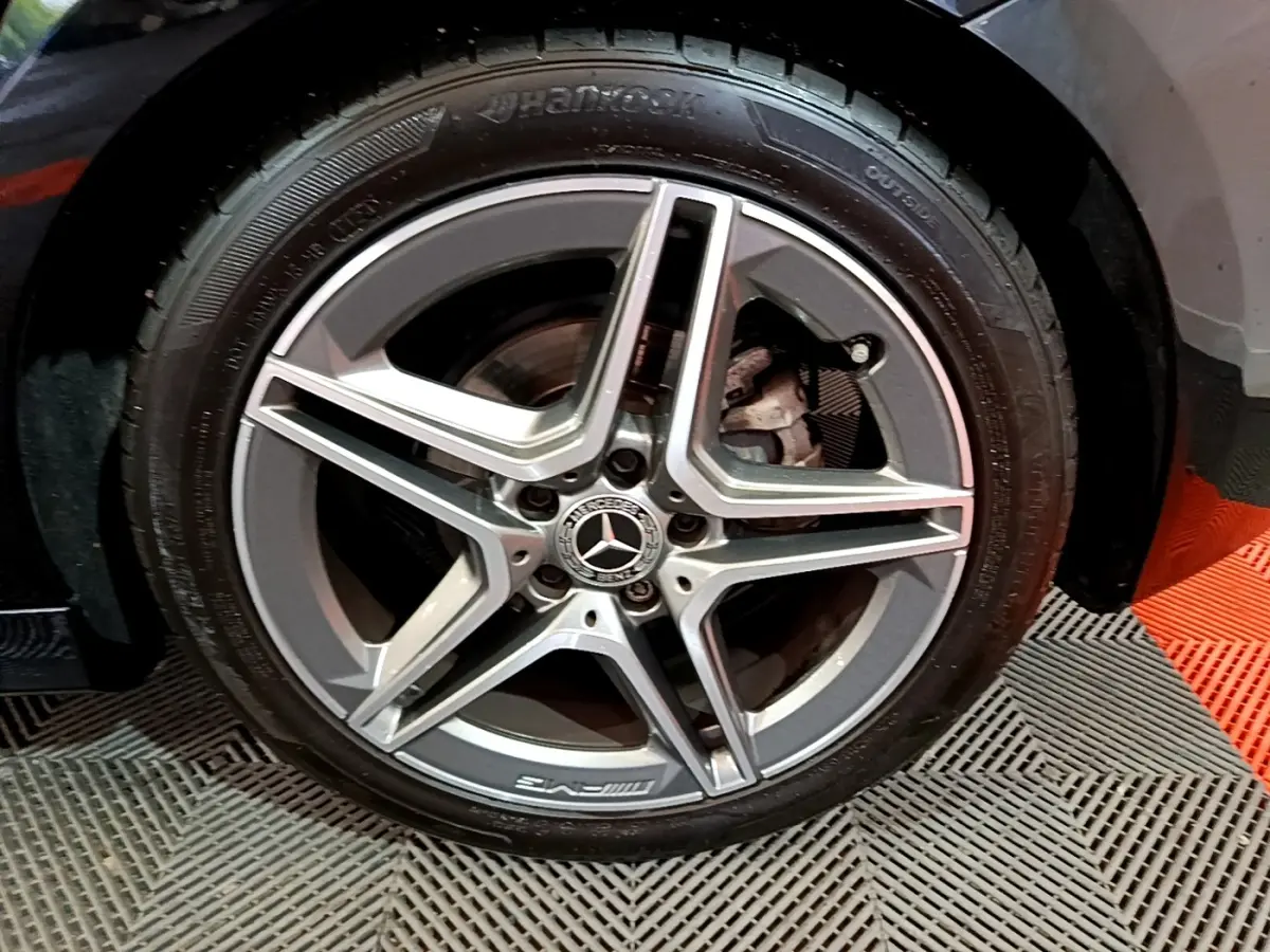 Gros plan sur la jante AMG en alliage gris avec logo Mercedes sur la roue avant gauche d'une Classe A noire.
