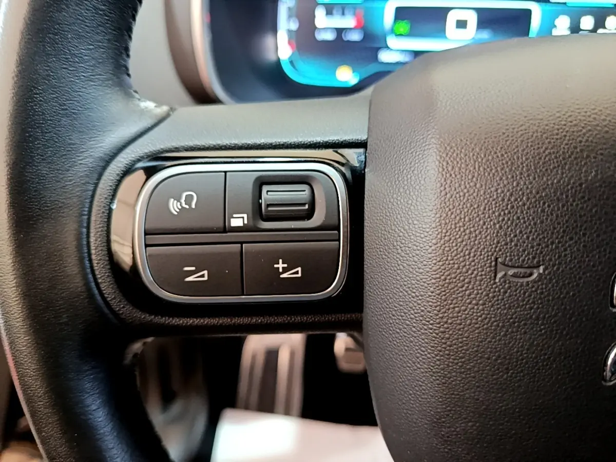 Gros plan sur les commandes multifonctions gauche du volant cuir noir du Citroën C5 Aircross 2020.