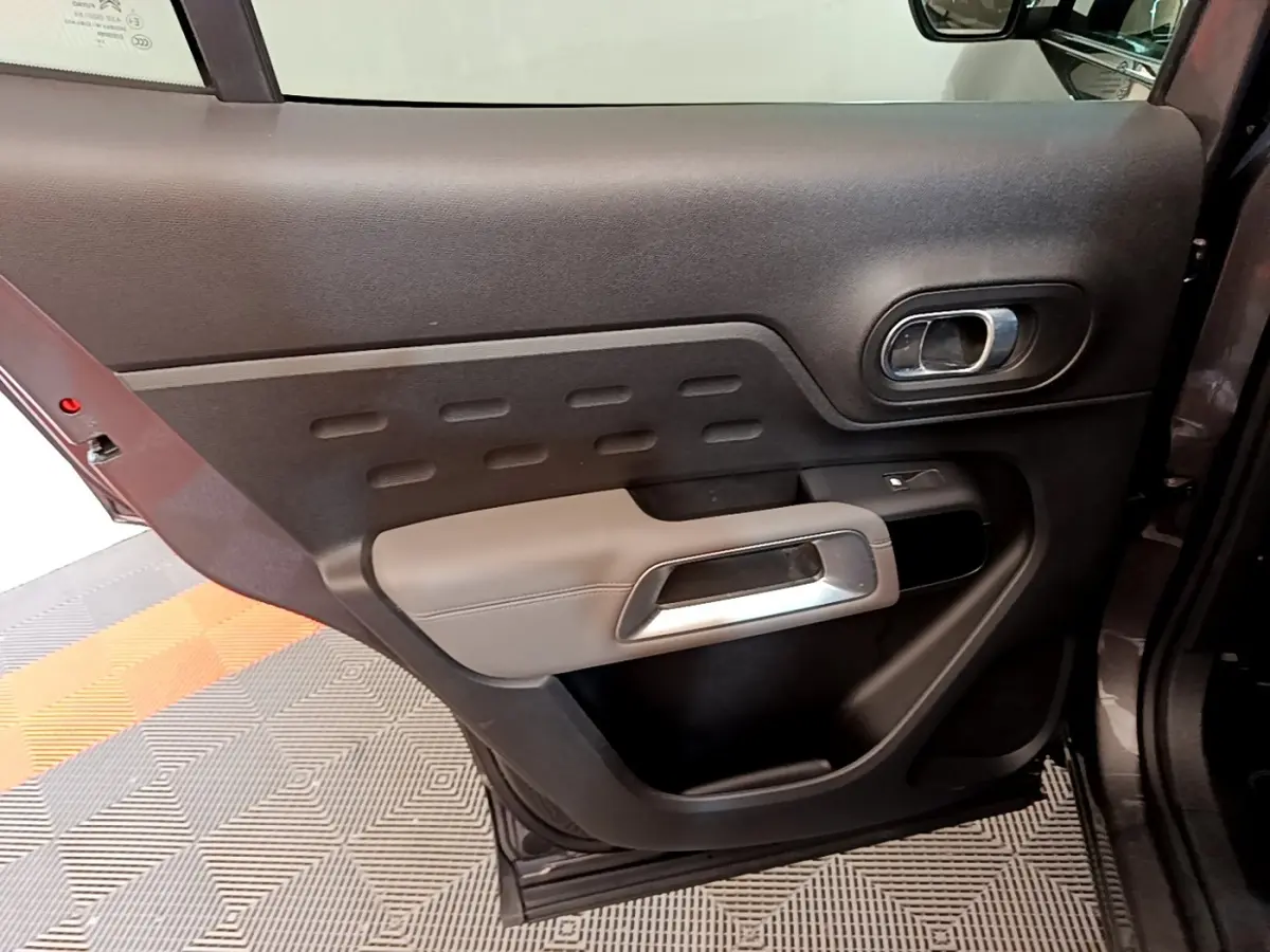 Vue intérieure de la porte arrière droite gris foncé du Citroën C5 Aircross avec poignée argentée et bouton de vitre électrique.