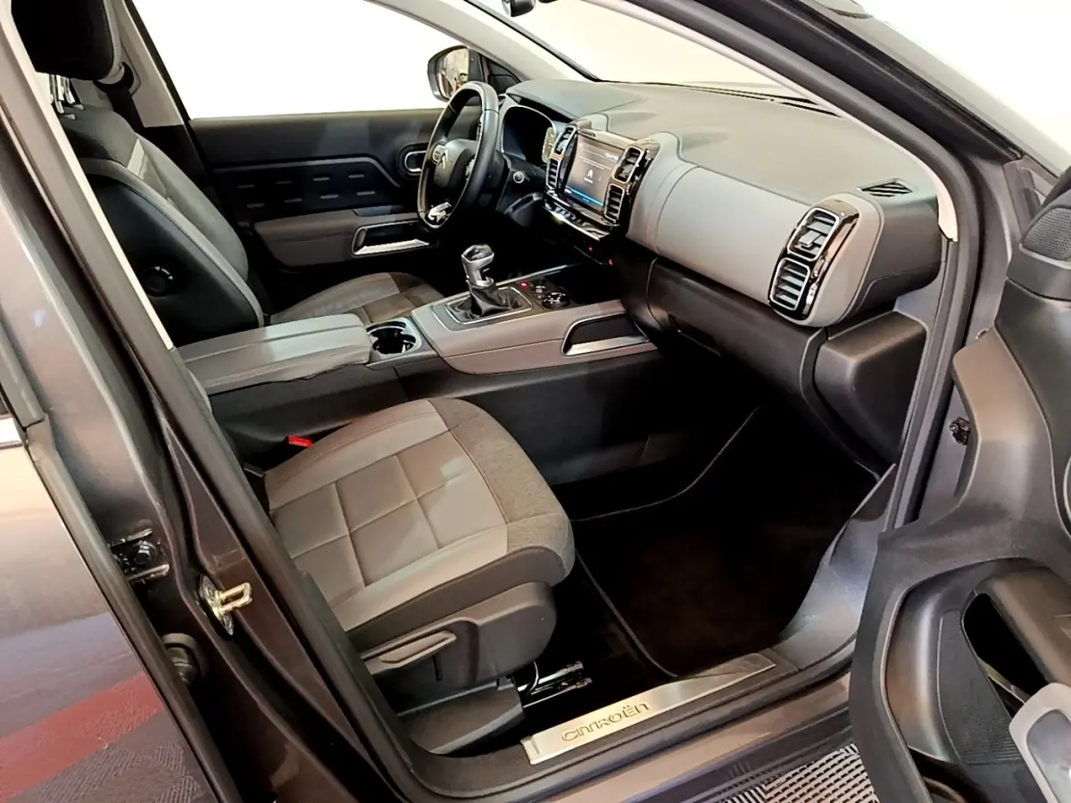 Intérieur côté conducteur de Citroën C5 Aircross gris foncé, volant cuir multifonctions et console centrale avec écran tactile.