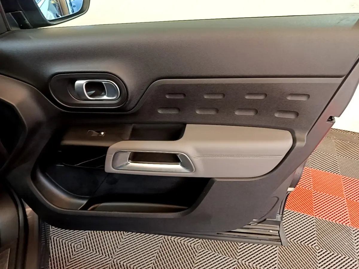 Vue intérieure du panneau de porte avant gauche du Citroën C5 Aircross 2020, avec accoudoir gris clair et poignée argentée.