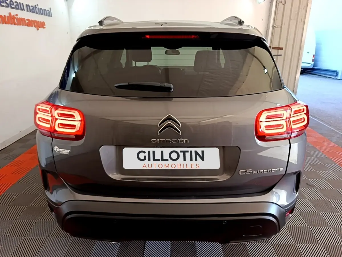 Vue arrière d'un Citroën C5 Aircross gris foncé avec feux arrière LED allumés dans un garage.