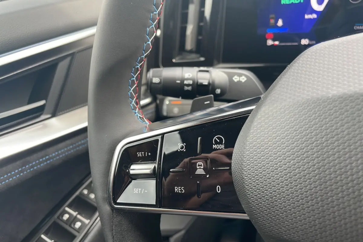 Gros plan sur les commandes au volant cuir noir avec surpiqûres tricolores du Renault Austral New 200 Esprit Alpine.