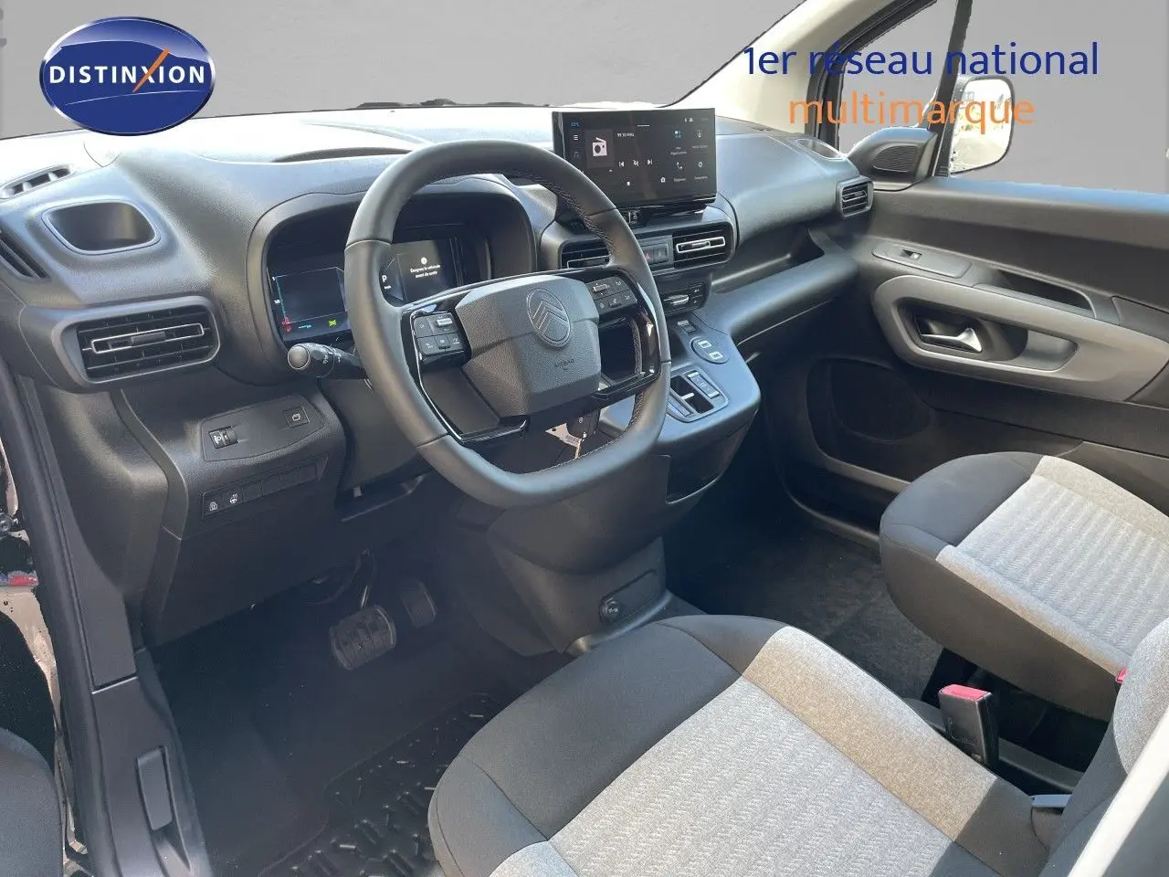 Vue intérieure côté conducteur du Citroën Berlingo 2026 noir, avec tableau de bord moderne et sièges tissu bicolore.