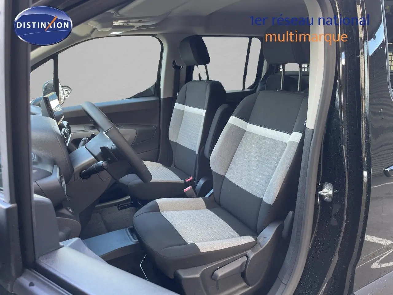 Vue intérieure côté conducteur du Citroën Berlingo noir Perla Nera, montrant les sièges tissu bicolores et le volant multifonction.