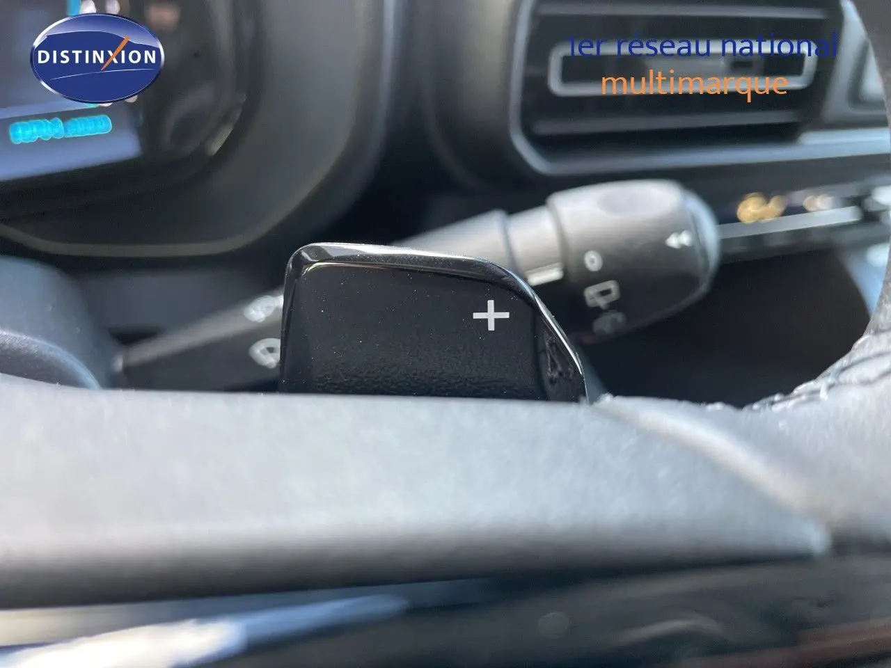 Gros plan sur la palette de changement de vitesse "+" au volant d'un Citroën Berlingo noir Perla Nera, intérieur sombre.