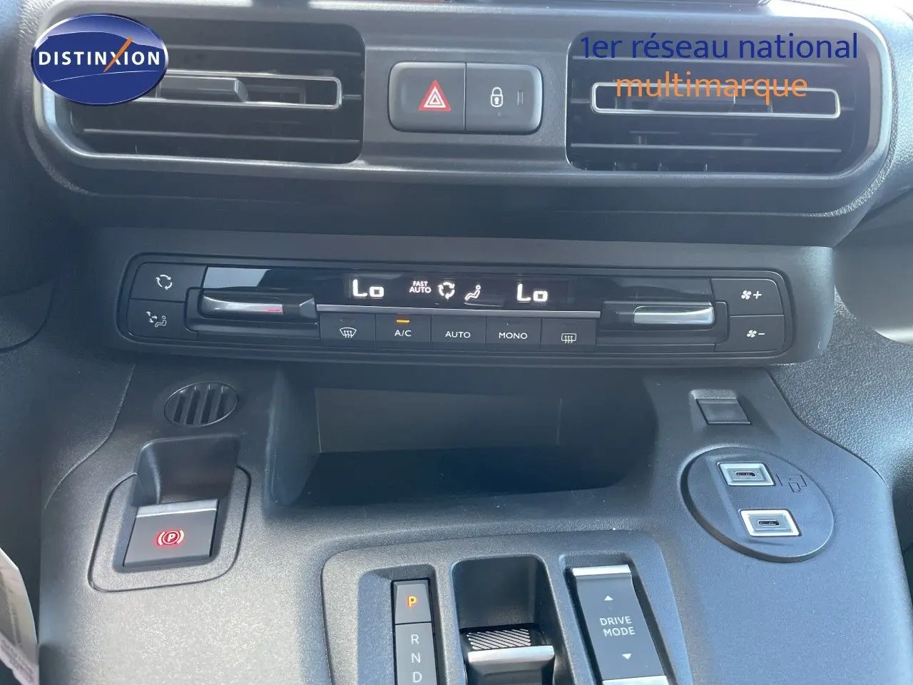 Vue rapprochée du tableau de bord et console centrale du Citroën Berlingo noir, avec commandes climatisation et boîte auto.