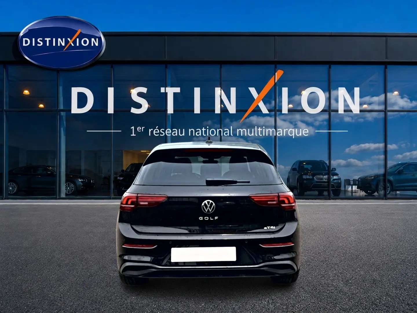 Vue arrière d'une Volkswagen Golf noire 2026 garée devant une vitrine avec logo Distinxion en arrière-plan.