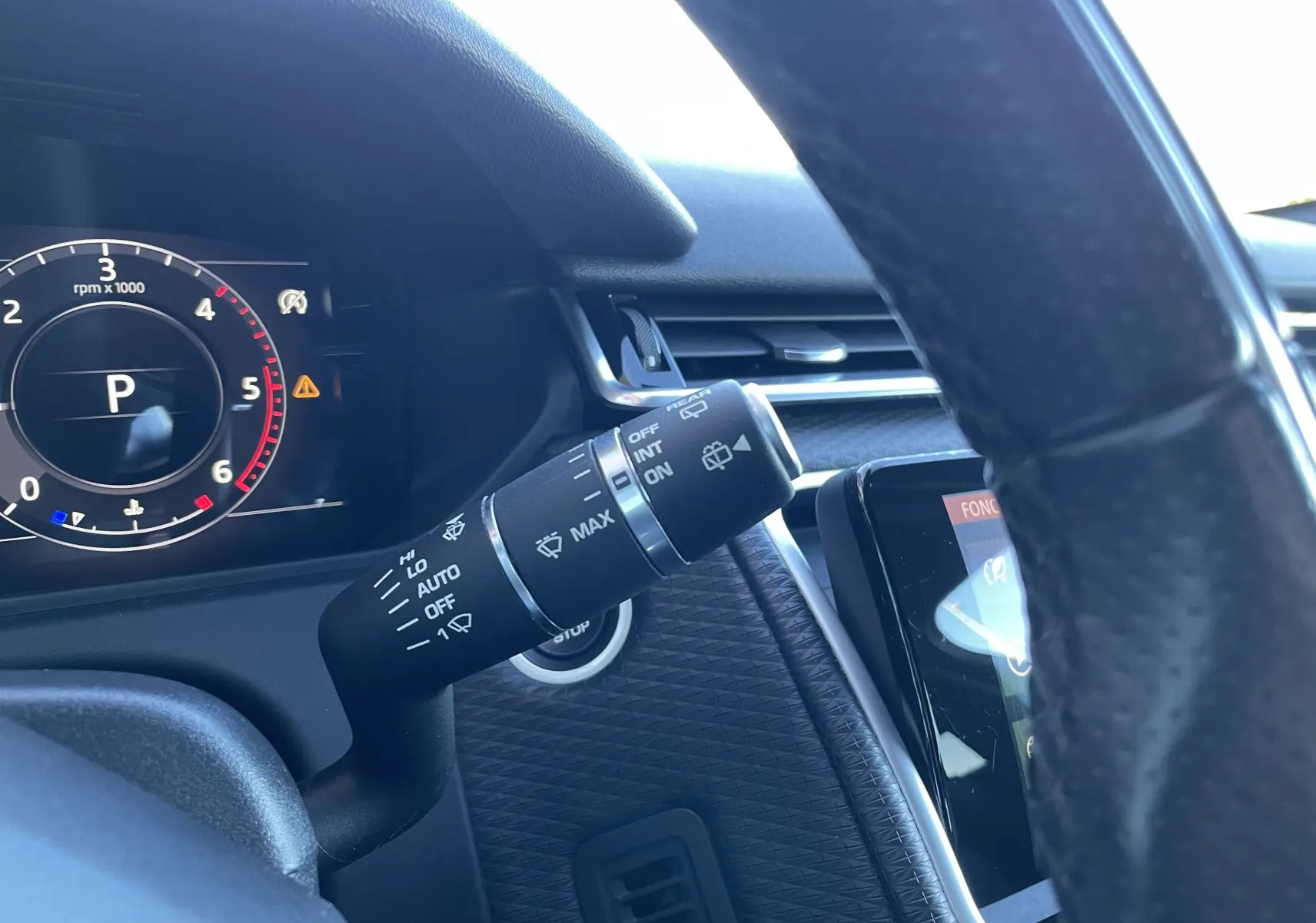 Gros plan sur la commande des essuie-glaces à gauche du volant dans l'habitacle gris noir du Range Rover Velar Corris Grey.