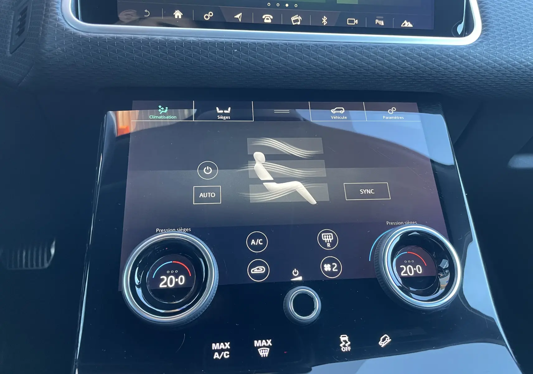 Tableau de bord du Range Rover Velar gris, vue rapprochée sur la commande tactile de climatisation à 20°C.