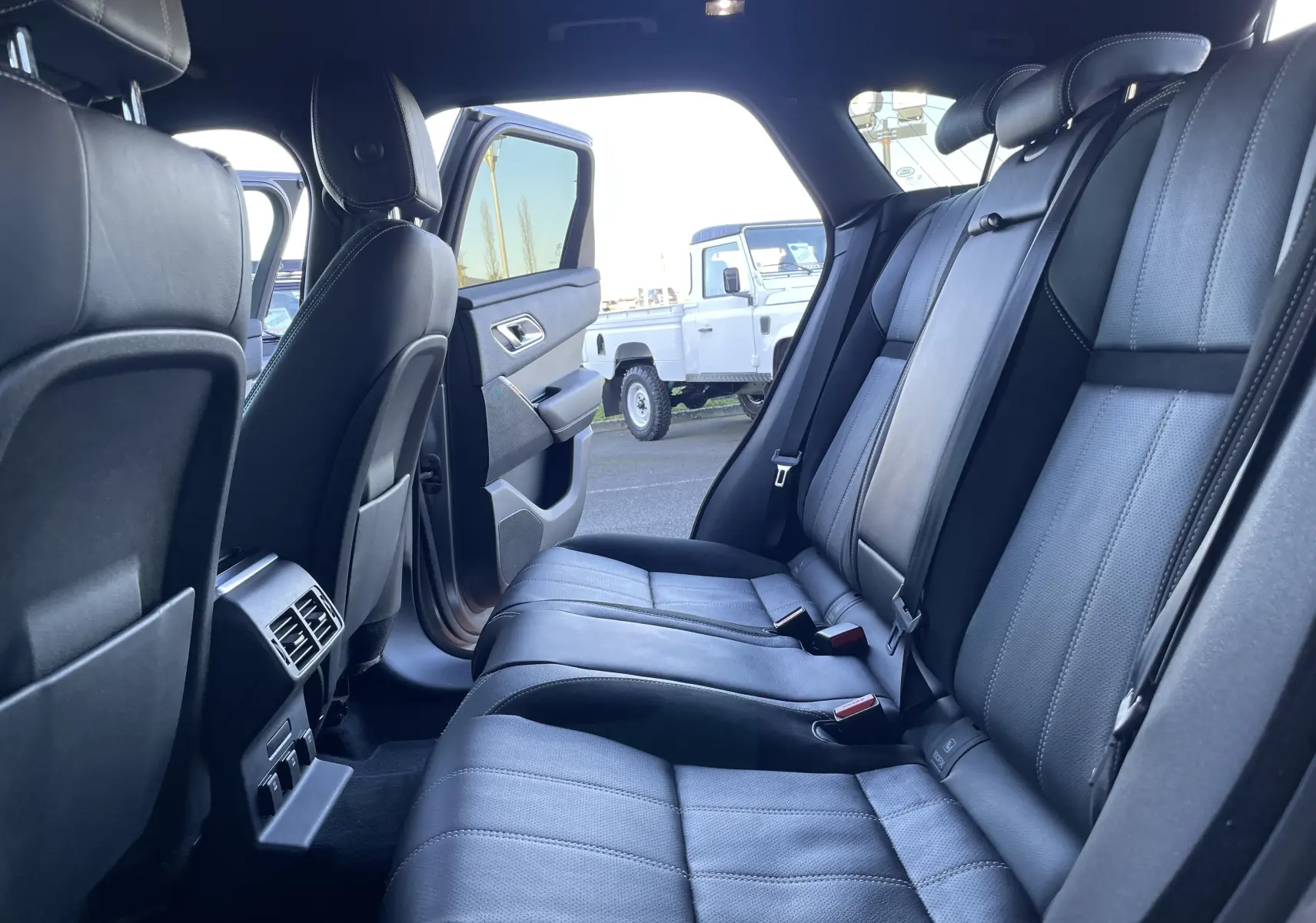 Vue intérieure arrière du Range Rover Velar D240 S R-Dynamic 2018, sièges cuir noir et porte arrière ouverte côté droit.