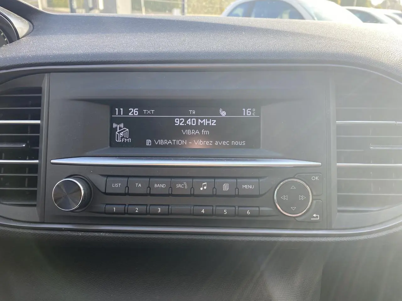 Tableau de bord de Peugeot 308 2017 avec radio affichant 92,40 MHz et commandes intégrées, ambiance intérieure noire.