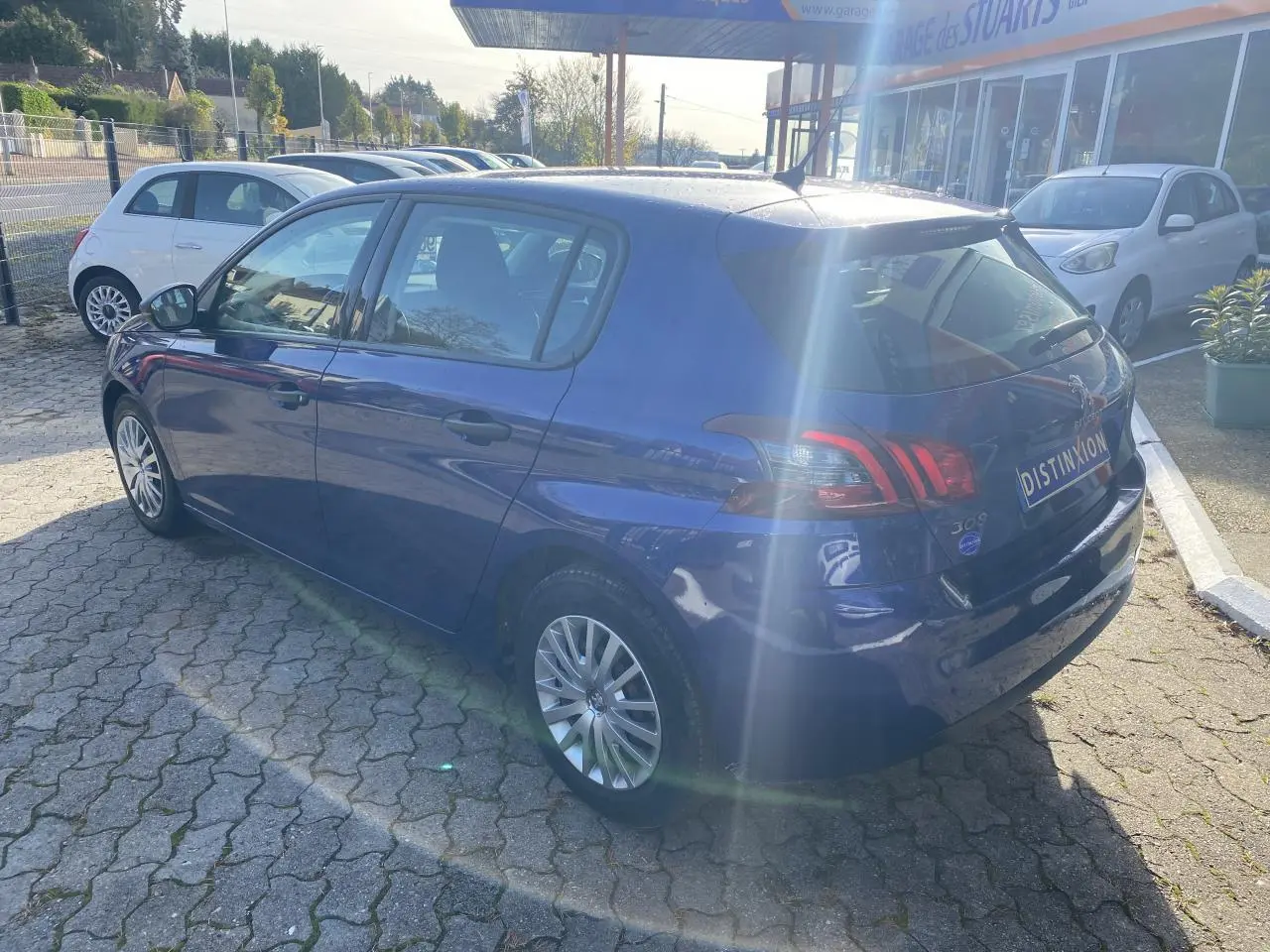Vue 3/4 arrière droite d'une Peugeot 308 bleu foncé métallisée de 2017 avec feux arrière distinctifs et jantes alliage.