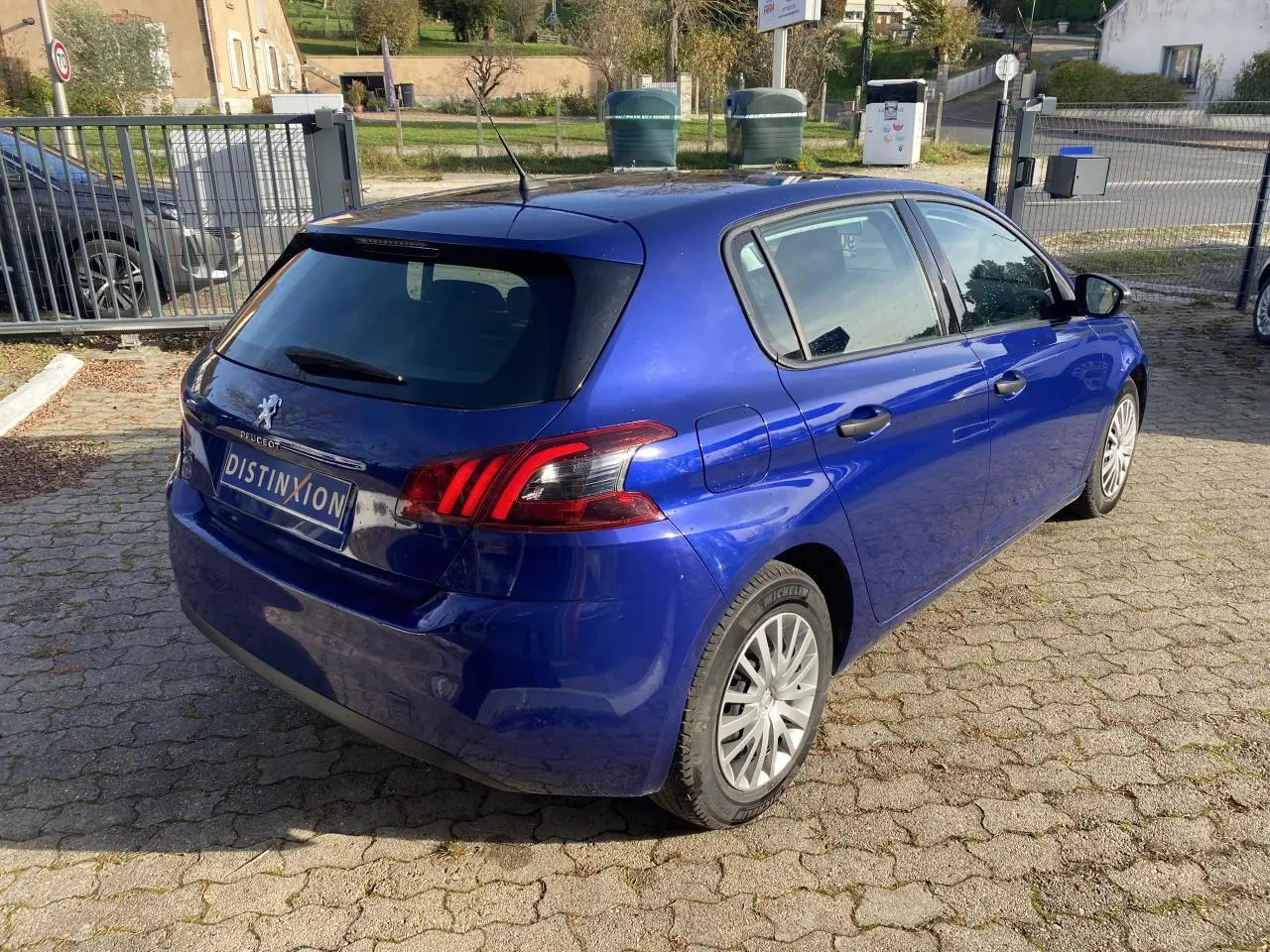 Vue 3/4 arrière droite d'une Peugeot 308 bleu foncé métallisé, avec feux arrière distinctifs et jantes alliage.