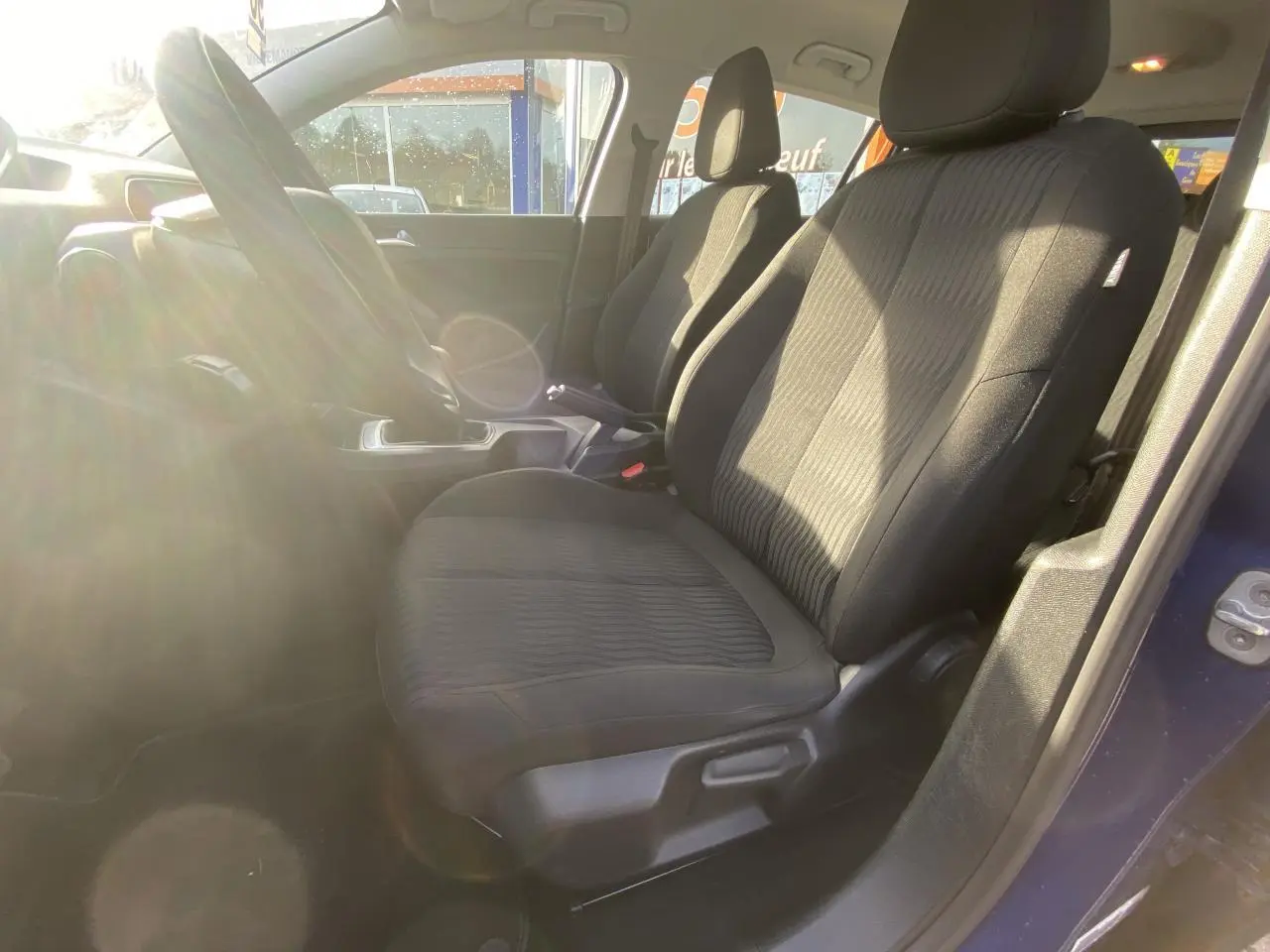 Vue intérieure côté conducteur de la Peugeot 308 bleu foncé 2017, montrant les sièges avant en tissu noir et le volant.