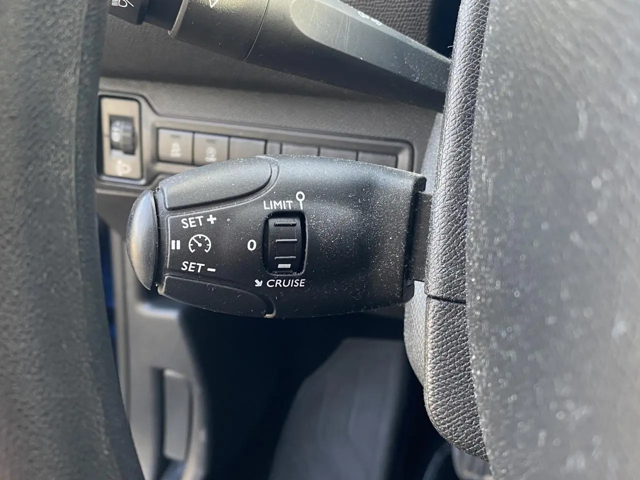 Gros plan sur la commande du régulateur de vitesse au volant d'une Peugeot 308 bleu foncé de 2017.