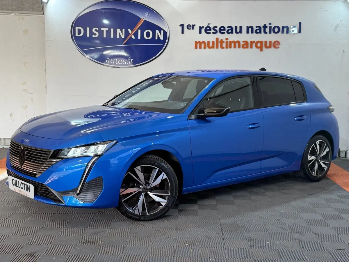 Peugeot 308 bleu en vue 3/4 avant droit, avec jantes alliage et calandre noire distinctive.