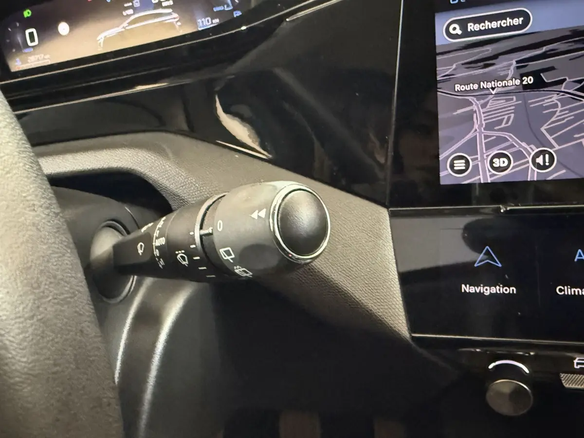 Gros plan sur la commande d'essuie-glace à gauche du volant dans l'habitacle noir de la Peugeot 308 2023.