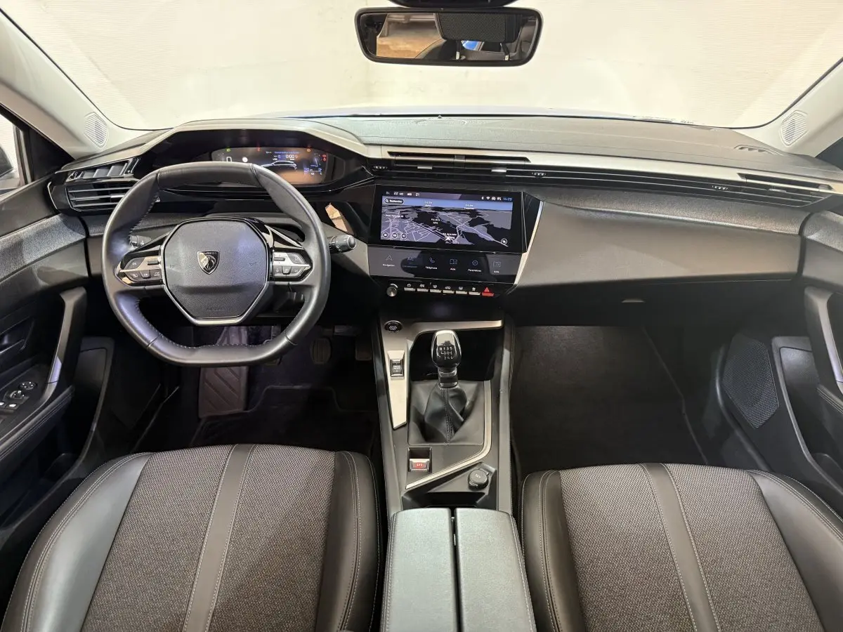 Vue intérieure avant de la Peugeot 308 PureTech 130 bleu, avec tableau de bord digital et volant cuir multifonctions.