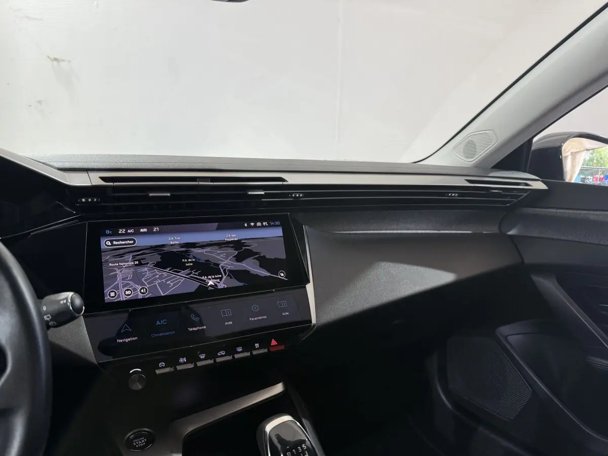 Vue intérieure côté passager du tableau de bord noir avec écran tactile de navigation de la Peugeot 308 bleu 2023 PureTech.