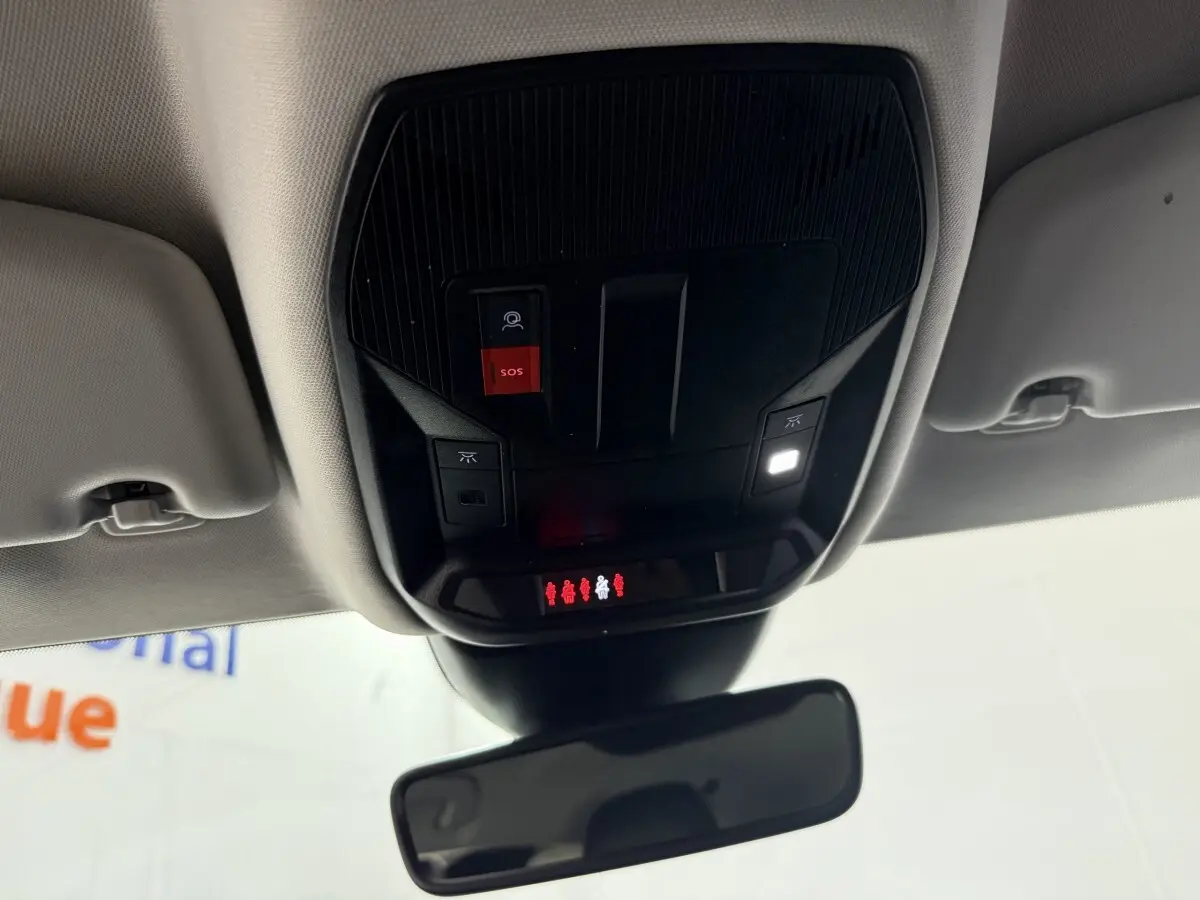 Vue intérieure du plafond avant de la Peugeot 308 bleu, montrant la console avec bouton SOS rouge et éclairage LED allumé.