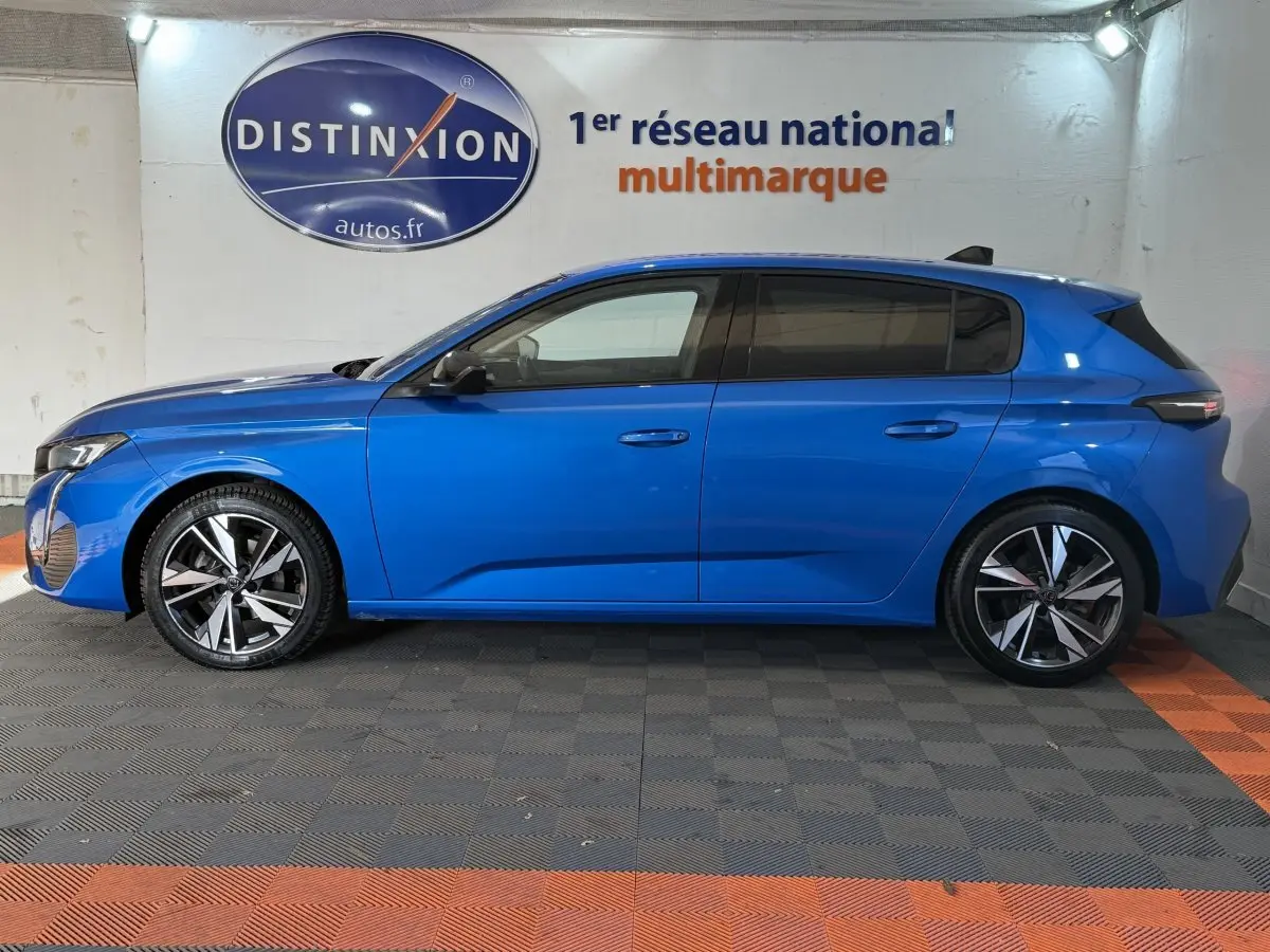 Peugeot 308 PureTech 130 S&S Allure Pack bleu vue de profil côté gauche en intérieur showroom.