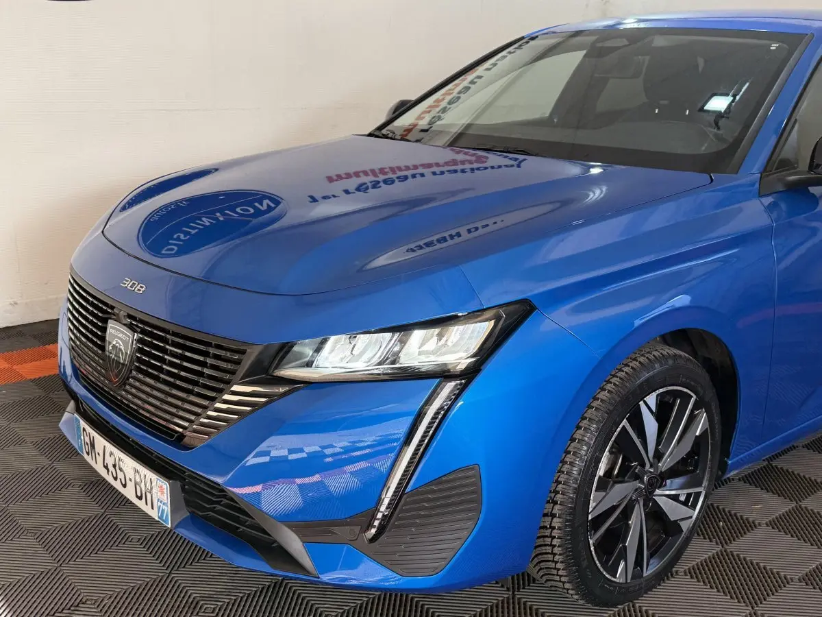 Vue 3/4 avant droit d'une Peugeot 308 bleu vif avec calandre noire et phares LED distinctifs.