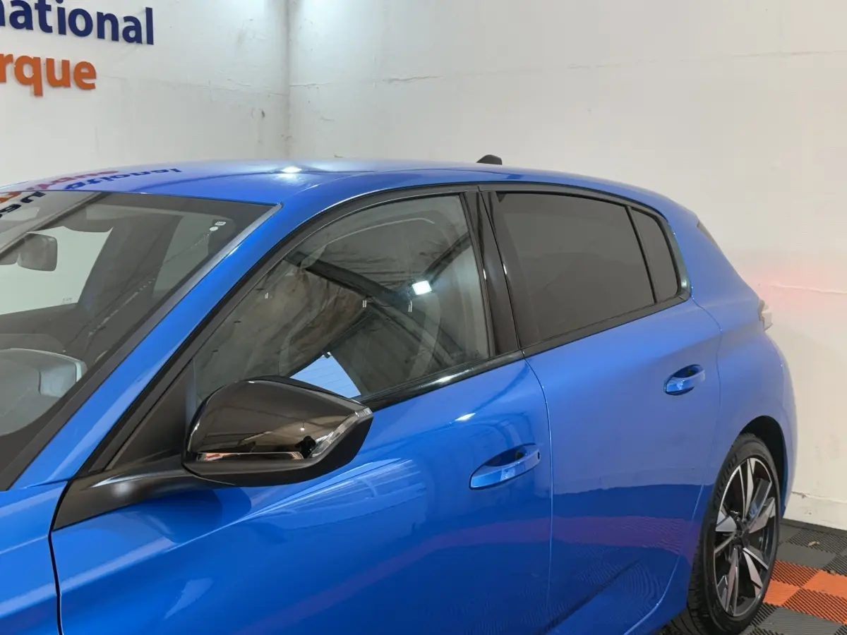 Vue latérale côté gauche d'une Peugeot 308 bleu vif avec vitres teintées et rétroviseur noir brillant.