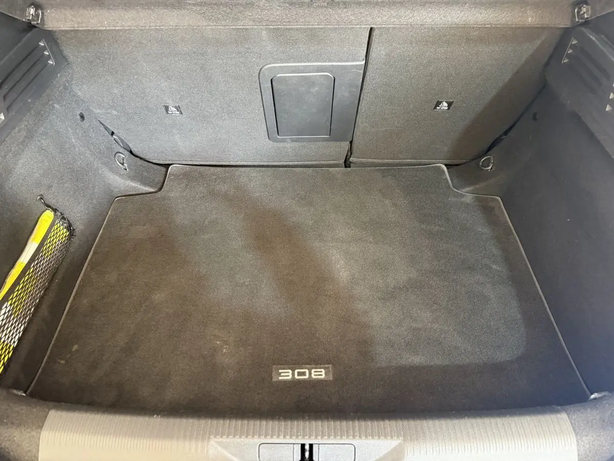 Coffre spacieux noir de la Peugeot 308 PureTech 130 S&S Allure Pack 2023, avec tapis marqué "308" vu de dessus.