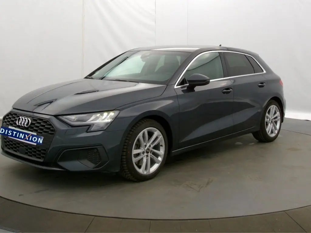 Audi A3 Sportback gris Manhattan vue 3/4 avant droit, mettant en valeur ses lignes modernes et jantes alliage.
