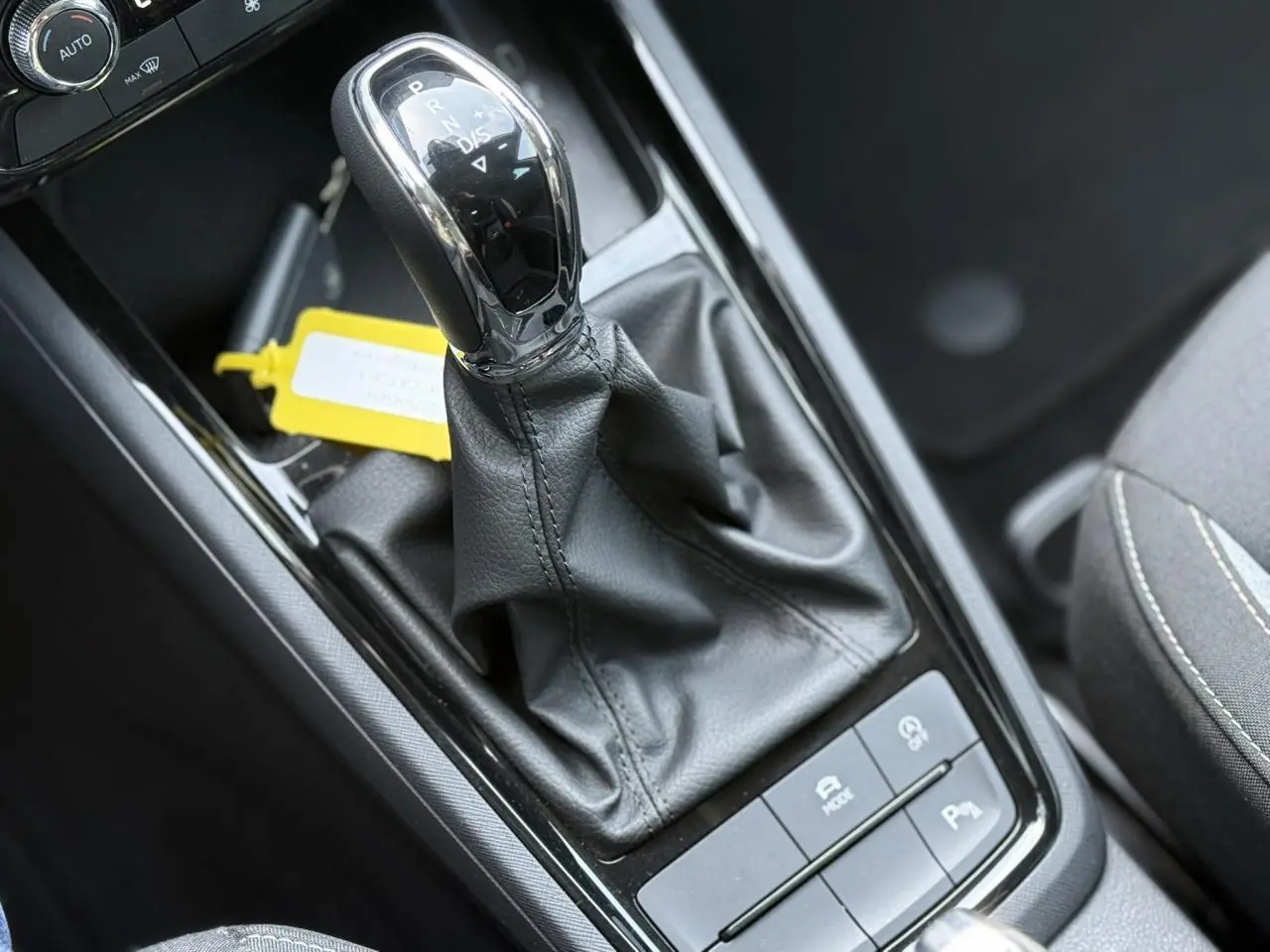 Gros plan sur le levier de vitesses automatique noir et chrome de la Skoda Scala TSI 116 DSG7 Sélection, intérieur gris.