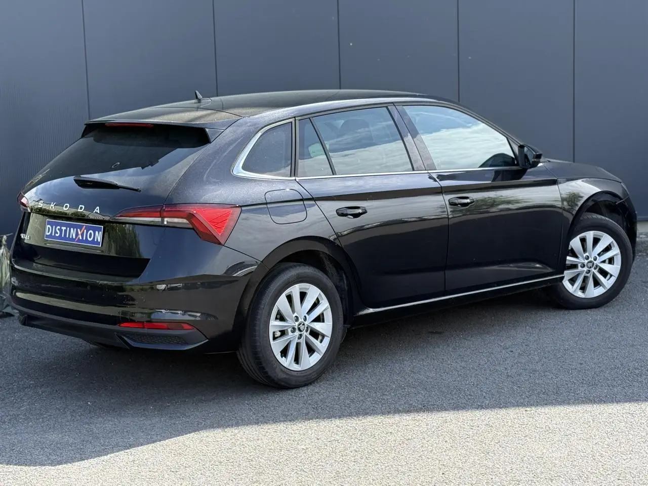 Vue 3/4 arrière côté droit d'une Skoda Scala noire Magic Perle avec jantes alliage 16 pouces et vitres surteintées.