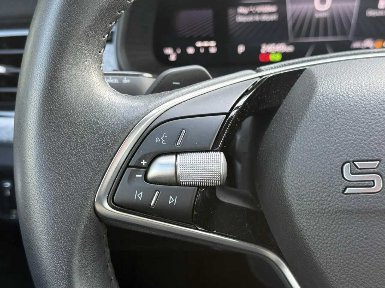 Gros plan sur la partie gauche du volant cuir noir du Skoda Scala 2025 avec commandes multifonctions et molette métallique.