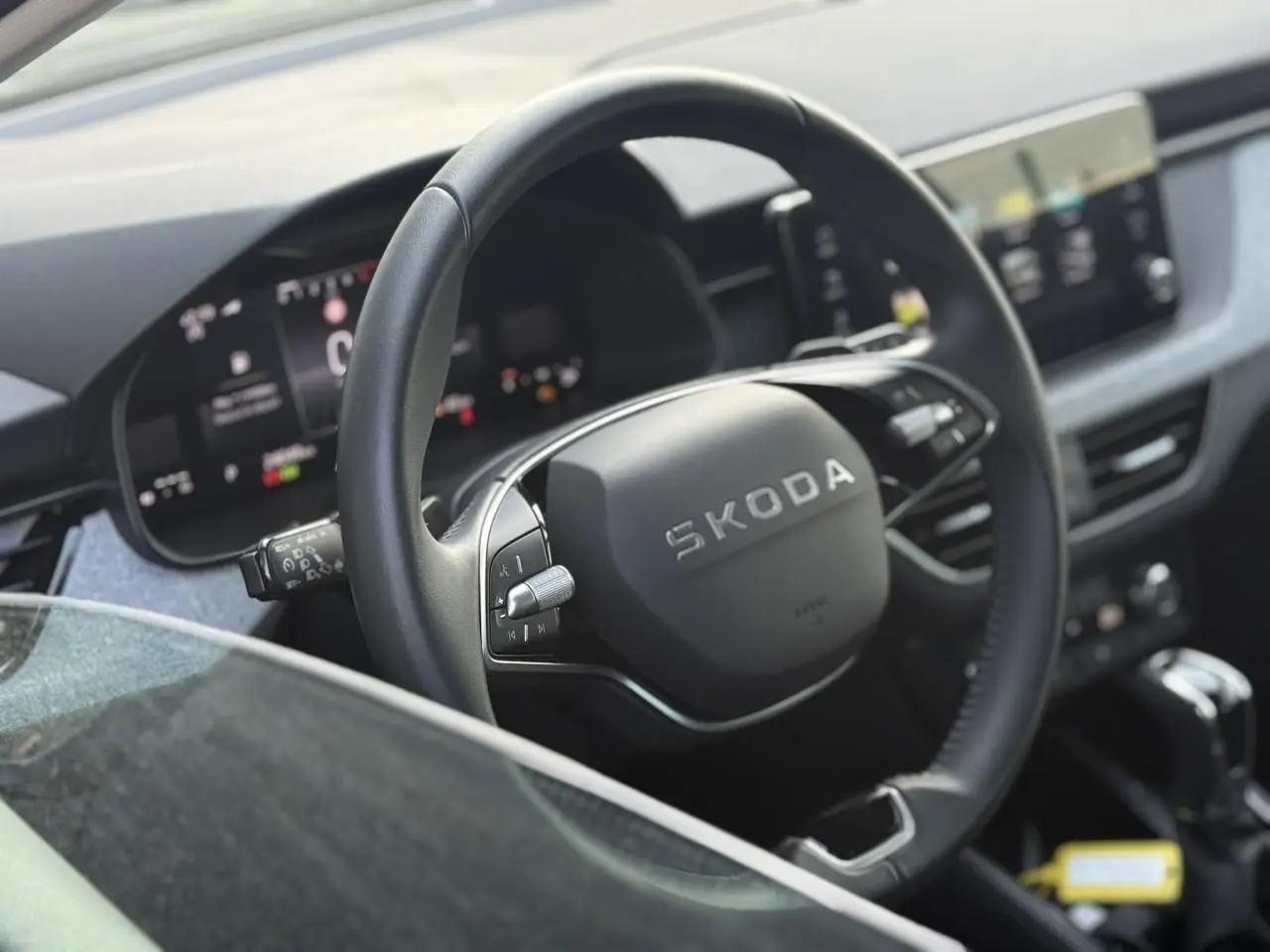 Vue rapprochée du volant en cuir noir multifonctions d’une Skoda Scala 2025, avec tableau de bord digital en arrière-plan.