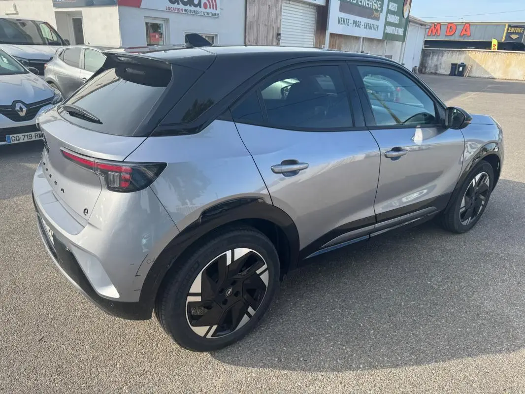 Vue 3/4 arrière droite de l'Opel Mokka électrique gris avec toit noir et jantes alliage 17 pouces.