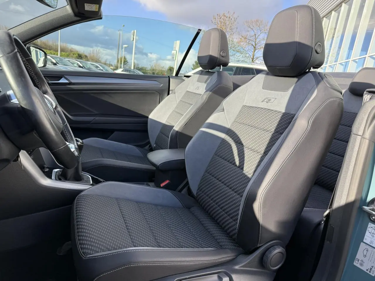 Vue intérieure côté gauche des sièges avant sport-confort gris et noirs du Volkswagen T-Roc Cabriolet vert cactus 2021.