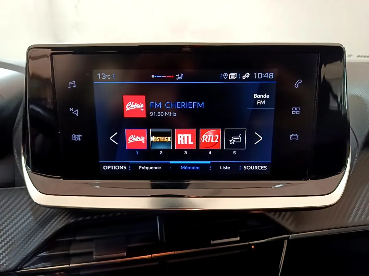 Écran tactile central du tableau de bord du Peugeot 2008 gris clair, affichant les stations radio FM