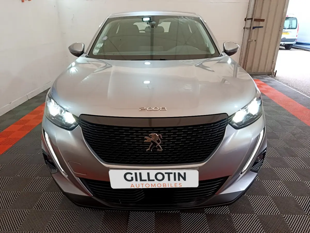 Peugeot 2008 gris clair vue de face avec phares LED allumés et calandre noire distinctive.