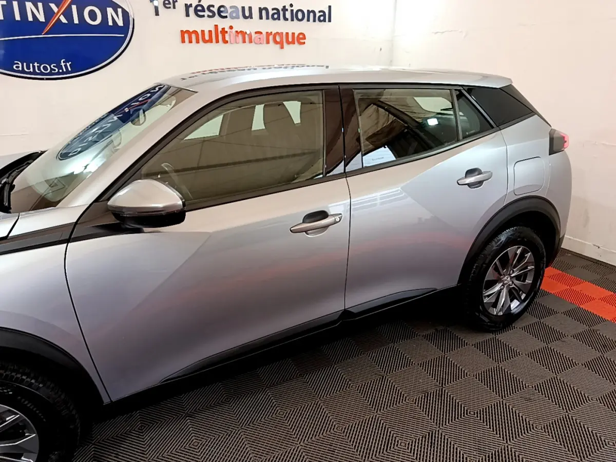 Profil côté gauche du Peugeot 2008 gris clair 2020, mettant en valeur ses lignes modernes et ses jantes alliage.