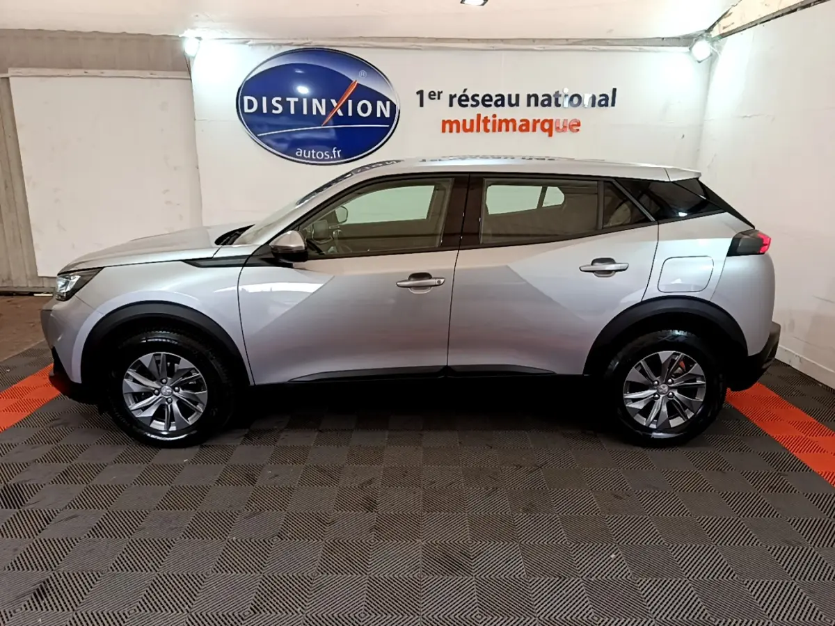 Peugeot 2008 gris clair vue de profil côté gauche, avec jantes alliage et lignes anguleuses modernes.