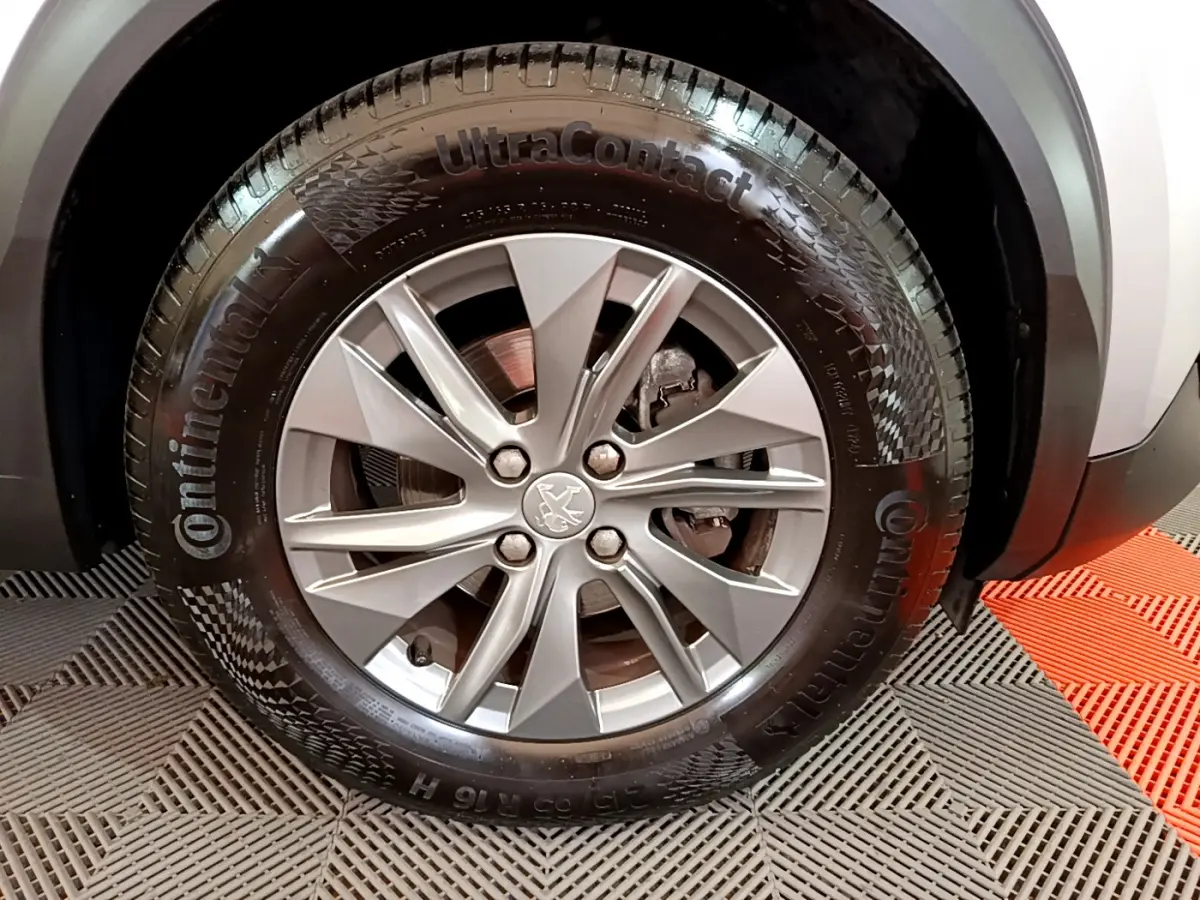 Gros plan sur la roue avant droite du Peugeot 2008 gris clair, mettant en valeur la jante alliage et le pneu Continental.