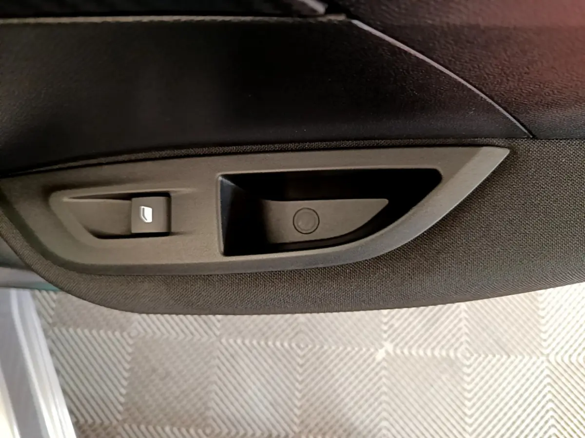 Poignée intérieure de porte côté gauche en plastique noir sur Peugeot 2008 gris clair, vue rapprochée.