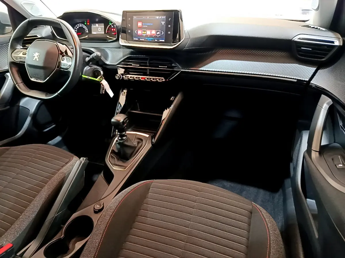 Intérieur avant du Peugeot 2008 2020 avec volant cuir, tableau de bord tactile et sièges tissu gris à surpiqûres rouges.