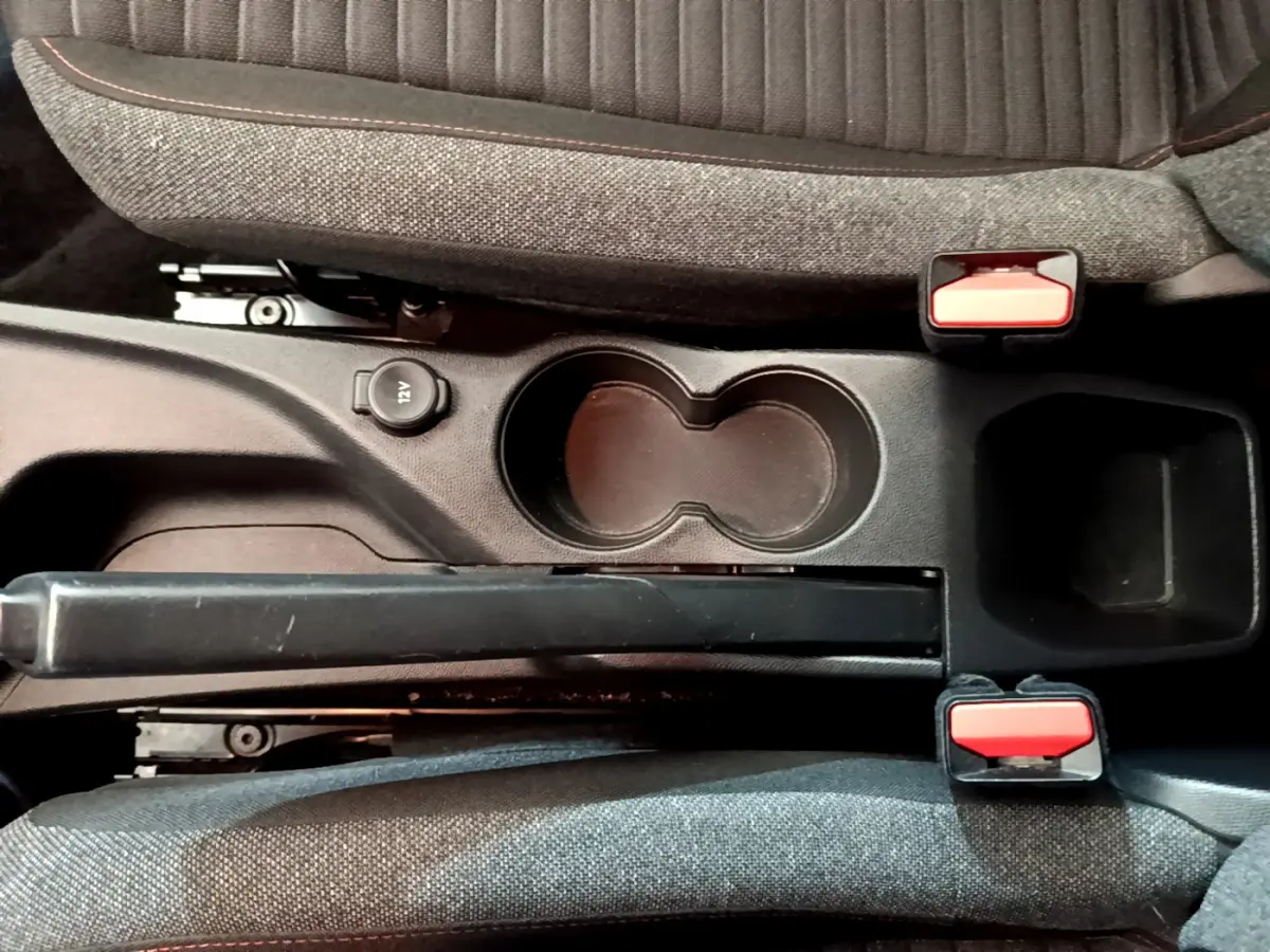 Vue plongeante sur la console centrale noire avec frein à main, porte-gobelets et sièges tissu gris du Peugeot 2008 2020.