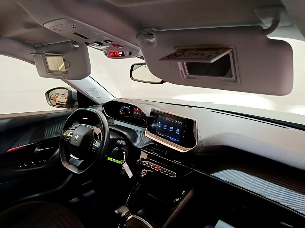 Vue intérieure côté conducteur du Peugeot 2008 2020, tableau de bord noir avec écran tactile et volant cuir multifonctions.