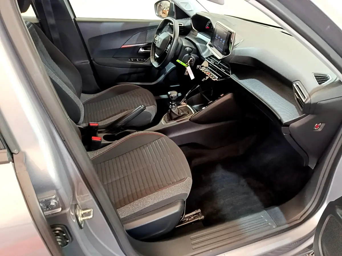 Intérieur avant droit du Peugeot 2008 gris clair 2020, avec tableau de bord moderne et sièges tissu noirs.