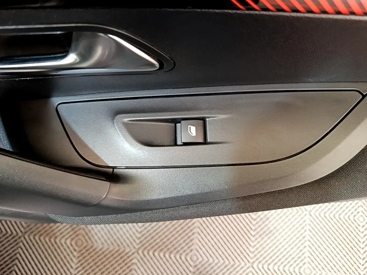 Bouton de commande de lève-vitre sur la porte intérieure côté conducteur d'une Peugeot 2008 gris clair de 2020.