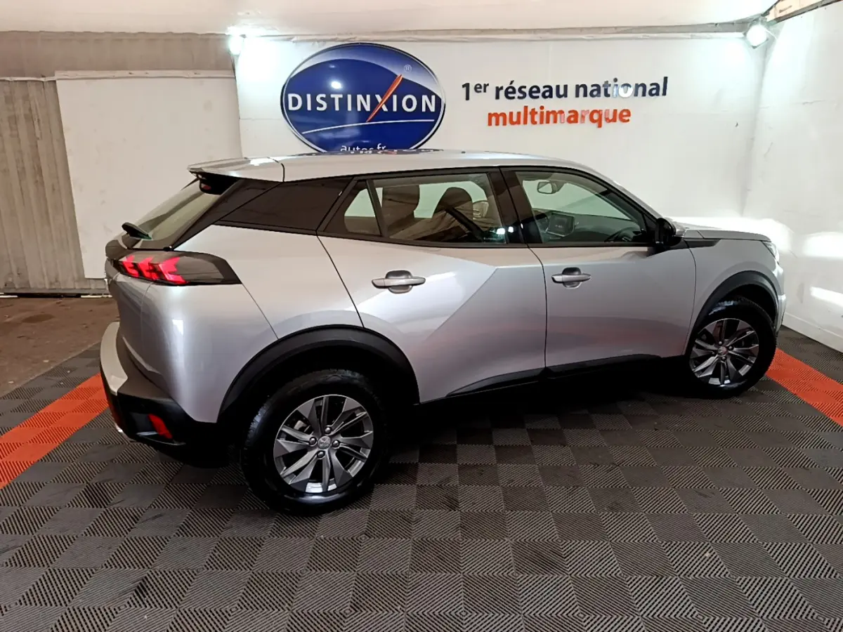 Peugeot 2008 gris clair vue de profil côté droit dans un showroom avec logo Distinxion en arrière-plan.